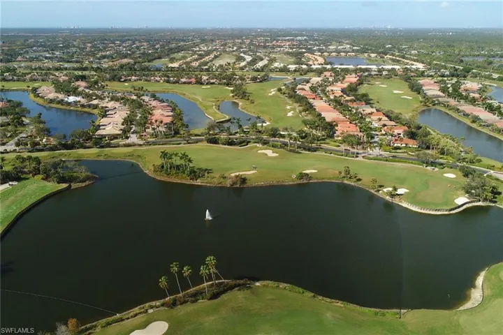 View of property location featuring a golf club, a large body of water, and nearby suburban area