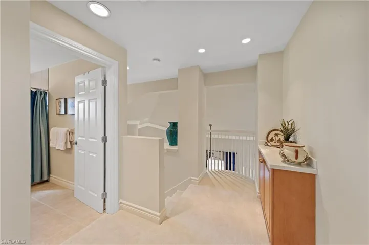 Corridor with an upstairs landing, recessed lighting, light carpet, and light tile patterned flooring