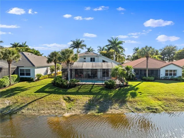 Back of property with a sunroom, a yard, and a water view