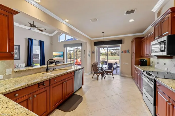 Kitchen featuring tasteful backsplash, stainless steel appliances, light stone countertops, pendant lighting, and brown cabinetry