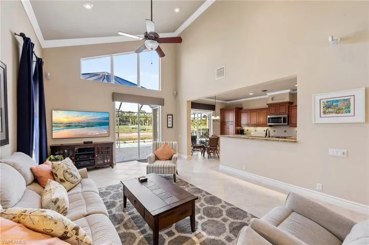 Living area with ornamental molding, ceiling fan, light tile patterned floors, recessed lighting, and a towering ceiling