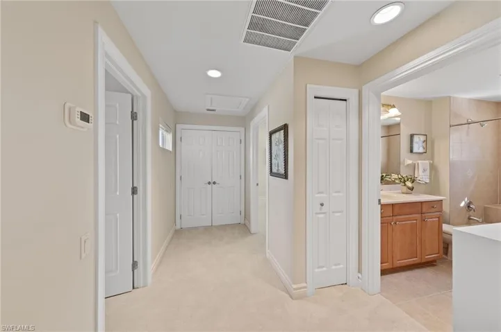 Corridor featuring light carpet, attic access, recessed lighting, and light tile patterned flooring