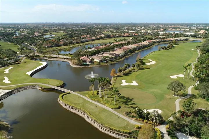 Aerial view of property and surrounding area with a golf course and nearby suburban area
