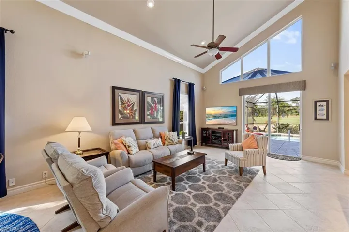 Living room featuring light tile patterned flooring, high vaulted ceiling, a ceiling fan, and ornamental molding