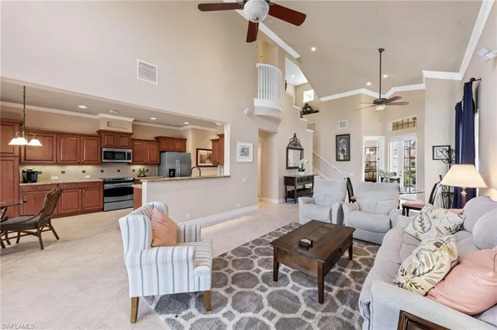Living room with high vaulted ceiling, ceiling fan, ornamental molding, light tile patterned floors, and recessed lighting