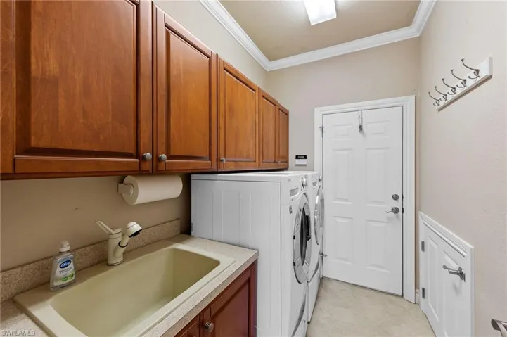 Laundry room with crown molding, washer and clothes dryer, and cabinet space