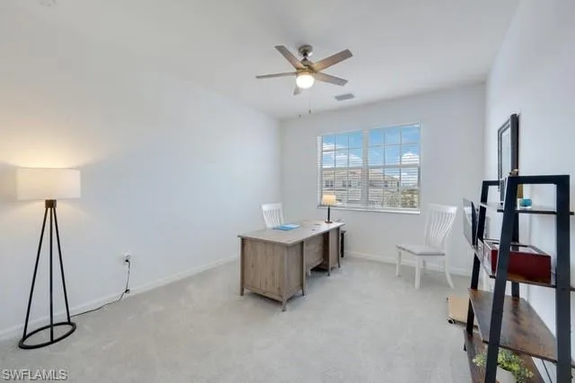 Office area with ceiling fan, light carpet, and baseboards