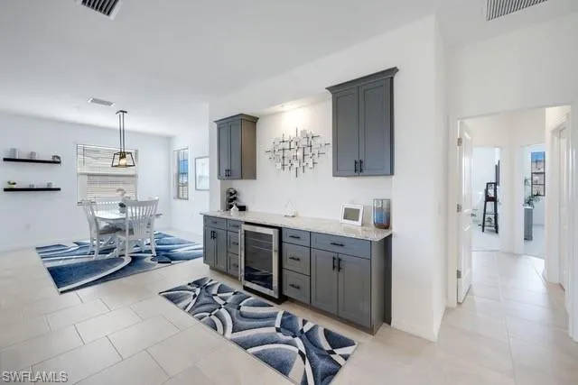 Dry bar featuring beverage cooler, wooden cabinets and granite countertop