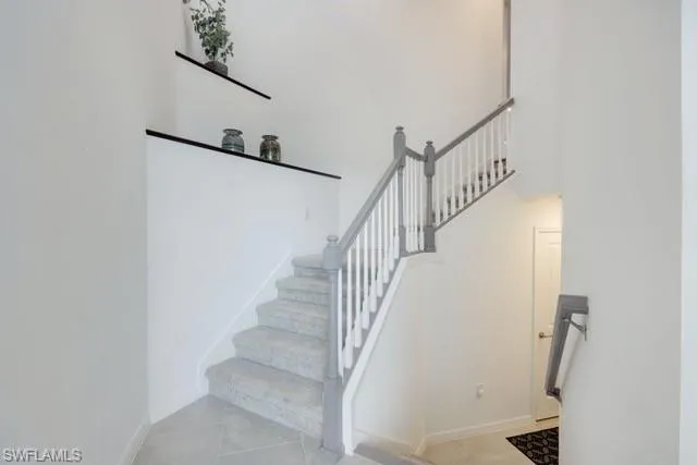 Stairs featuring baseboards and tile flooring and custom wood shelving