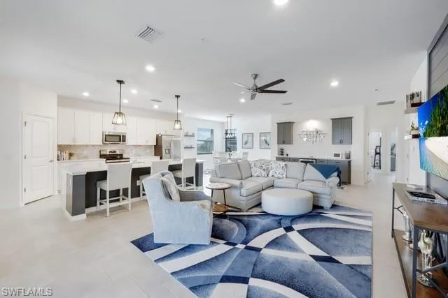Living room with ceiling fan, recessed lighting, and light tile patterned flooring