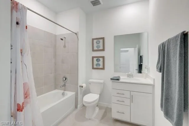 Full bathroom with toilet, shower / bathtub combination with curtain, vanity, tile patterned flooring, and baseboards