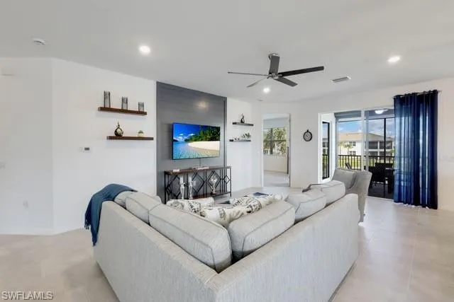 Living area with a ceiling fan, recessed lighting, light tile patterned floors, and baseboards