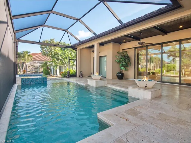 View of pool with an in ground hot tub, a patio, glass enclosure, and ceiling fan