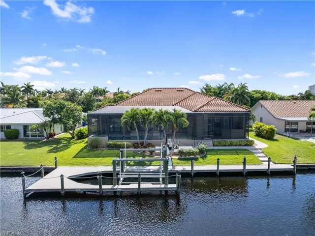 Back of house featuring a yard, a water view, and a lanai