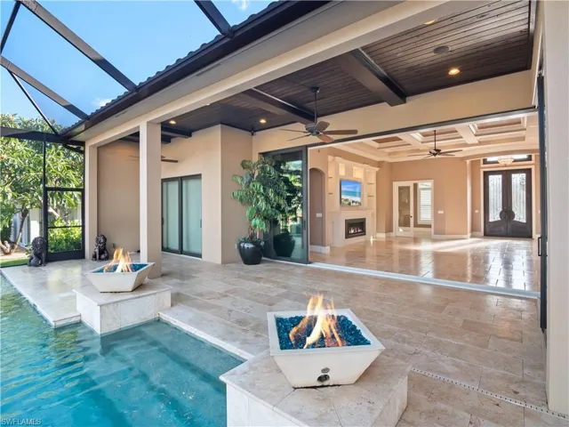 View of swimming pool with a fire pit, ceiling fan, a patio area, and a lanai