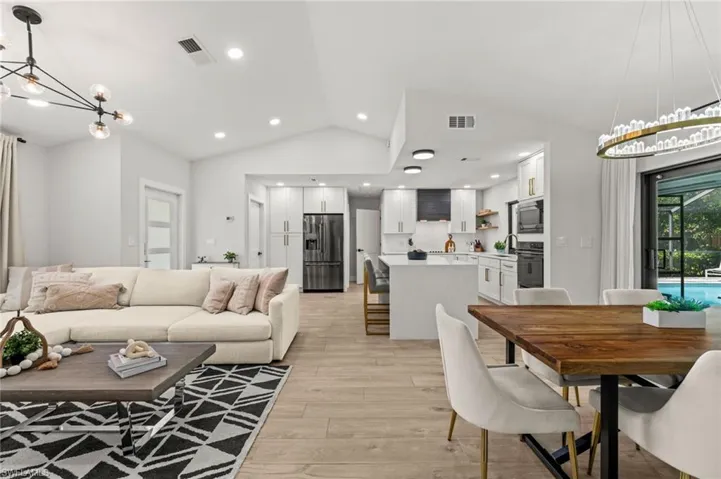 Living room with a chandelier, vaulted ceiling, and light wood-style floors