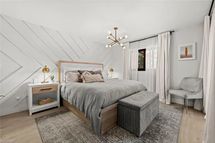 Bedroom featuring light wood-style flooring, hanging lights, and vaulted ceiling
