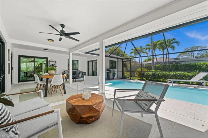 View of swimming pool with patio surround, grilling area, a sunroom, an outdoor living / dining area, and a lanai