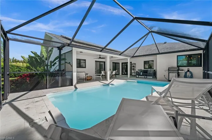 Swimming pool with glass enclosure, a sunroom, a patio, and a grill