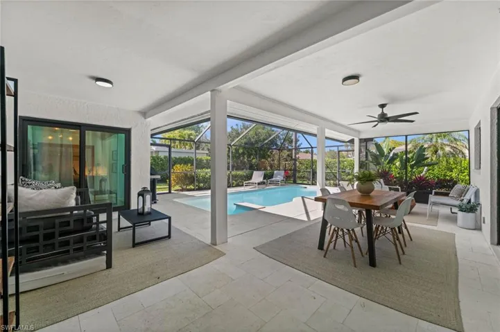 Outdoor pool with a patio area, a sunroom, outdoor lounge area, and glass enclosure