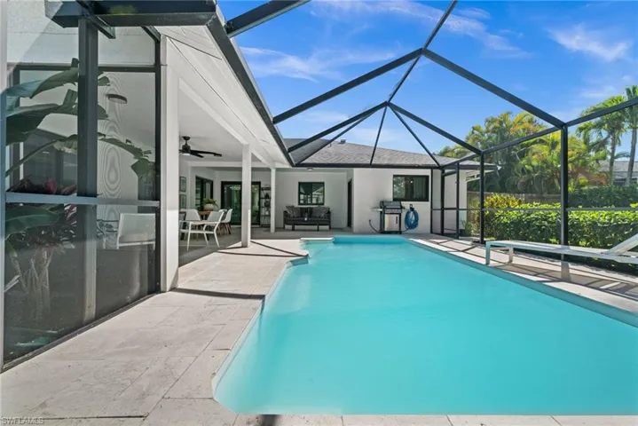 Swimming pool with a patio area, a sunroom, a lanai, and grilling area