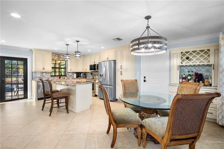 Dining space with crown molding, hanging lights, and light tile patterned floors