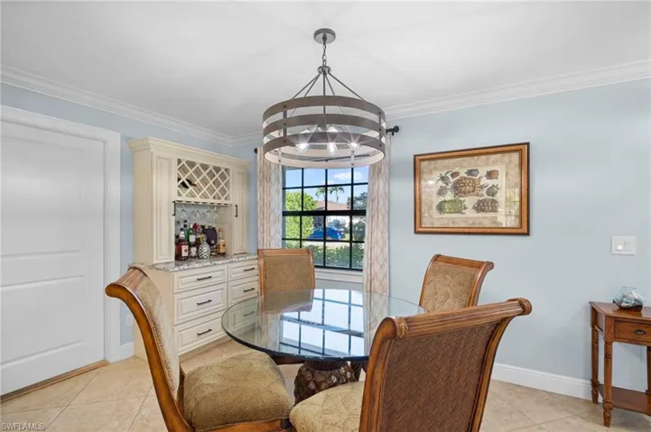 Dining room with hanging lights, crown molding, light tile patterned flooring, and a bar