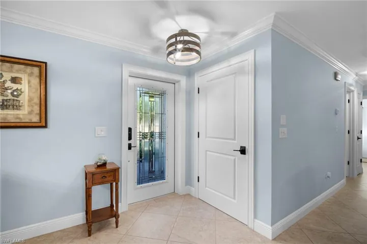 Foyer featuring ornamental molding, light tile patterned floors, and a chandelier