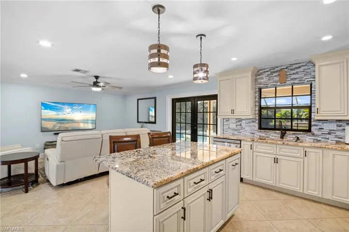 Kitchen featuring french doors, a center island, open floor plan, cream cabinets, and light stone counters