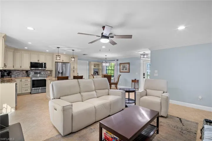 Living room with recessed lighting, ceiling fan, light tile patterned floors, and crown molding