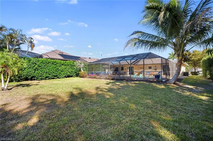 Back of house featuring a sunroom, a lanai, and a lawn