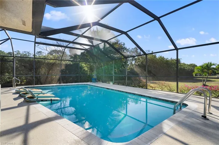 Outdoor pool with a sunroom, glass enclosure, and a patio area