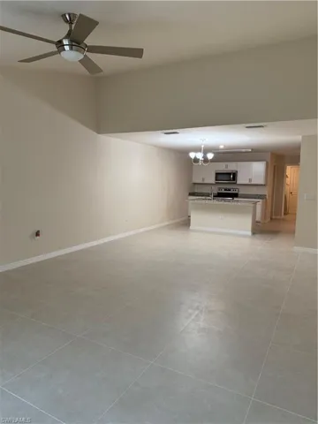 Unfurnished living room featuring a ceiling fan, a chandelier, and light tile patterned floors