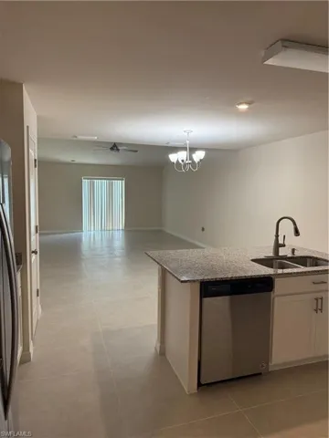 Kitchen with dishwasher, refrigerator, light stone countertops, and white cabinets