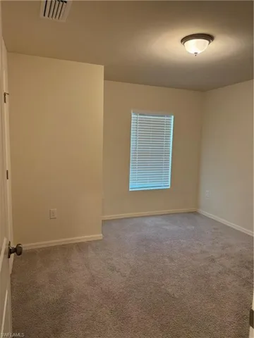 Spare room featuring carpet flooring and baseboards