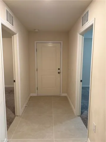 Hallway with light tile patterned floors and baseboards