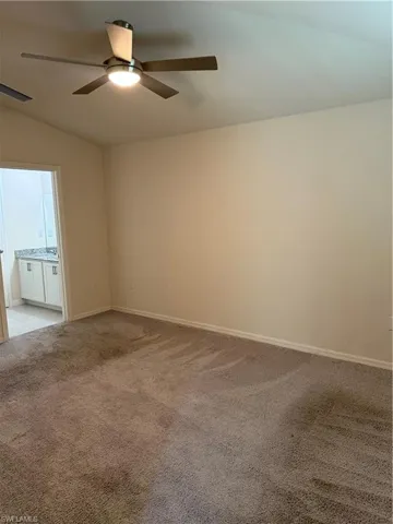 Spare room with a ceiling fan, lofted ceiling, and light carpet