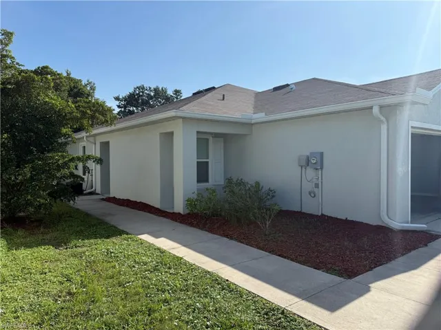 View of side of home featuring stucco siding, roof with shingles, and a lawn