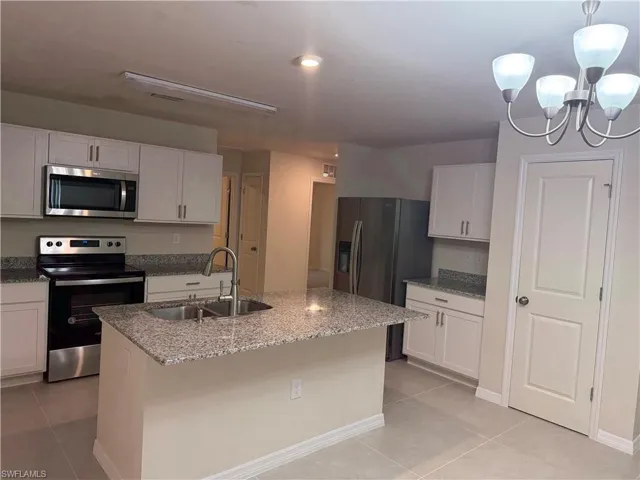 Kitchen with appliances with stainless steel finishes, light tile patterned flooring, and white cabinets