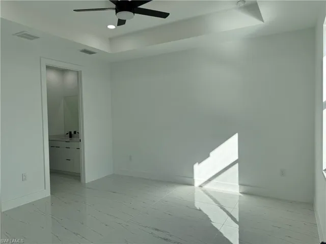 Empty room featuring a raised ceiling and ceiling fan