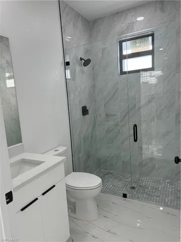 Bathroom featuring vanity, toilet, and a shower with shower door