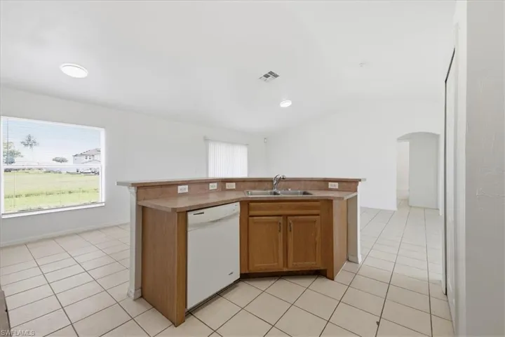 Kitchen featuring a peninsula with a double basin sink, wood-finish cabinetry, and a light-toned countertop