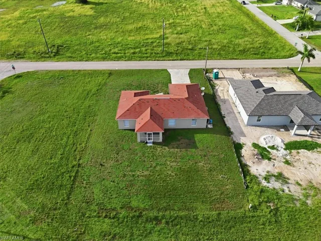Expansive green lot featuring a single-story residence with a red tile roof