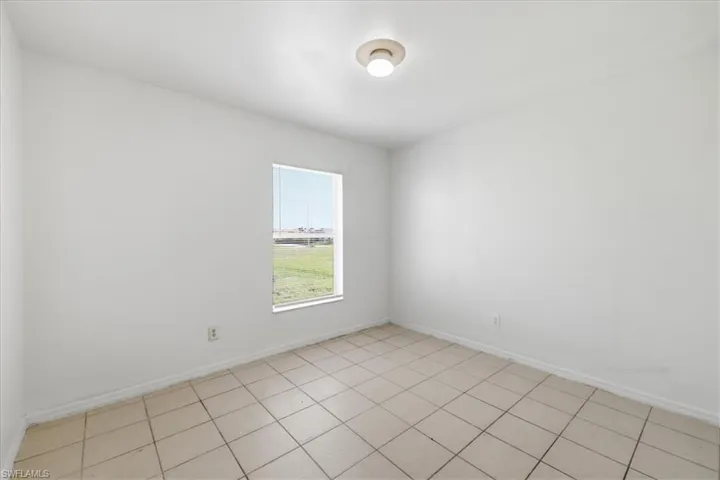 Room featuring neutral-toned tile flooring, white baseboards, and a single window with horizontal blinds