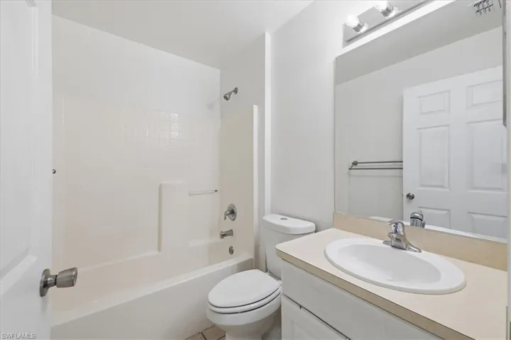 Bathroom featuring a white vanity with an oval basin sink, a large wall-mounted mirror, a tub/shower combination with white subway tile surround, and a chrome faucet
