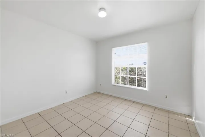 Room featuring a single paned window with grid, white walls, and light-colored tile flooring