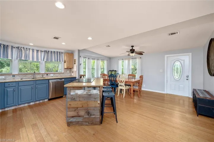 Kitchen featuring light wood-type flooring, tasteful backsplash, a kitchen island, and dishwasher
