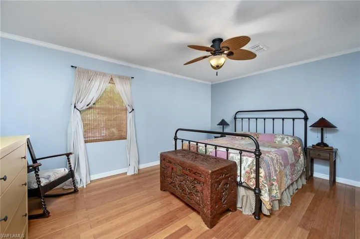 Bedroom with ornamental molding, ceiling fan, and light hardwood / wood-style floors