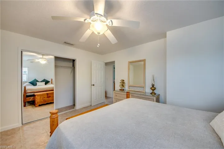 Bedroom with a closet, light tile patterned floors, and ceiling fan