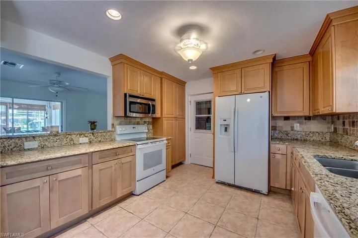 Kitchen featuring light tile patterned flooring, tasteful backsplash, white appliances, and ceiling fan